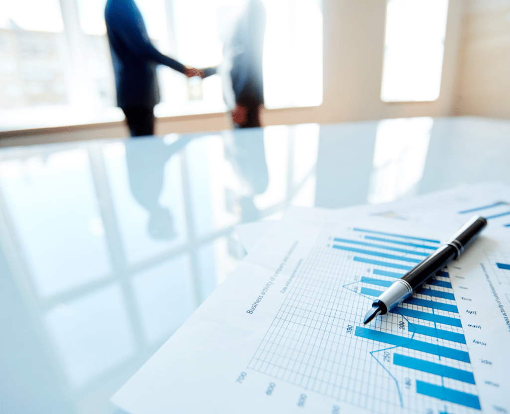 Two men shaking hands while a chart document sits on the conference room table
