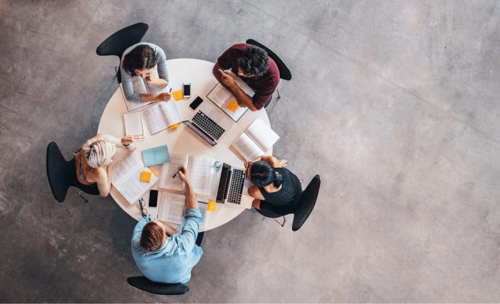 Five people sitting at a circular conference room table
