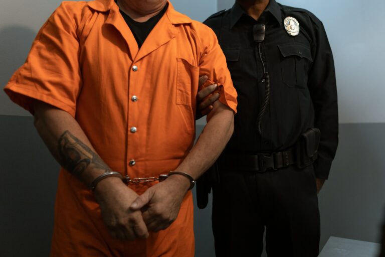 Inmate in handcuffs standing next to an officer