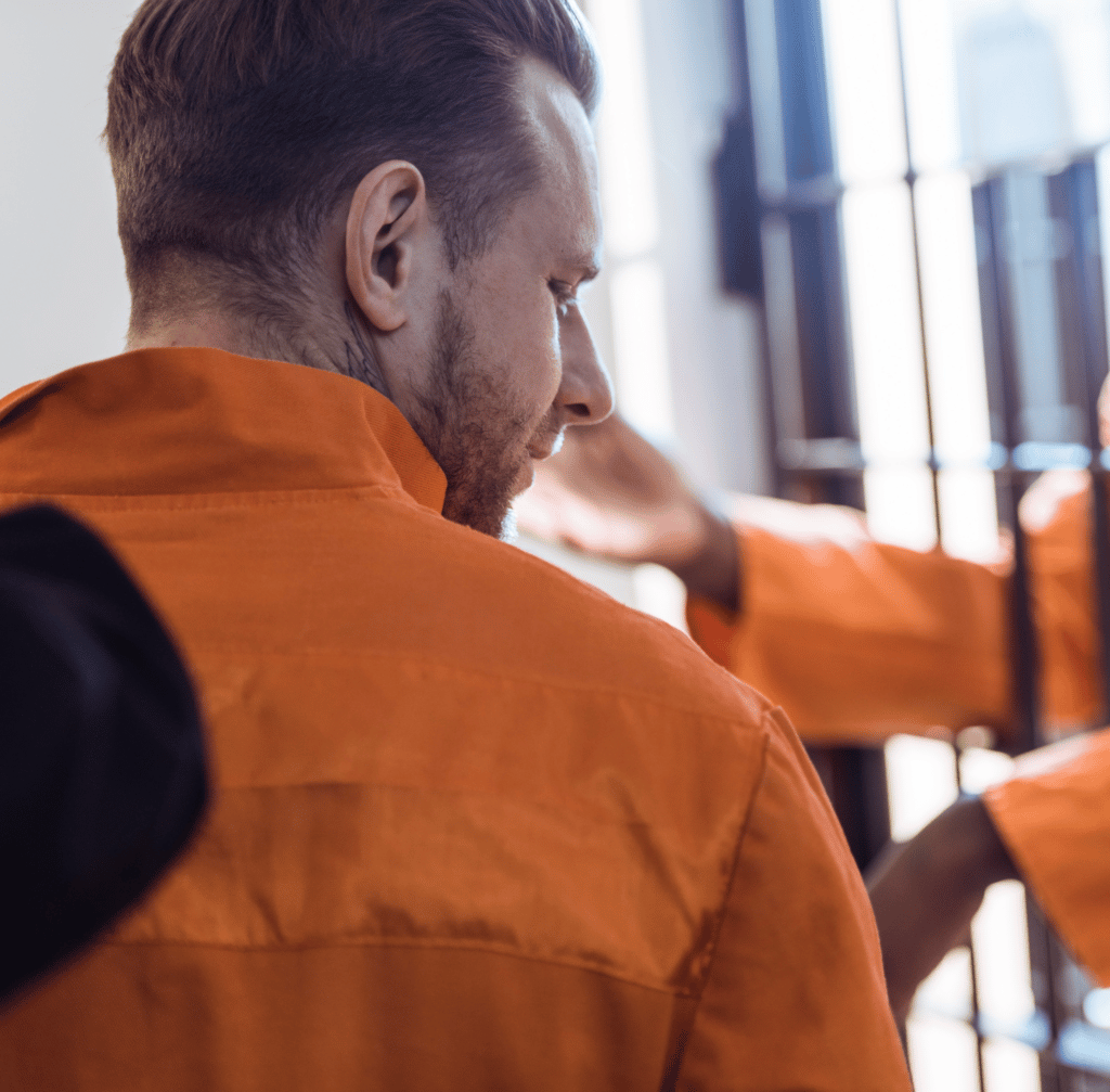 Cropped image of prison guard leading prisoner