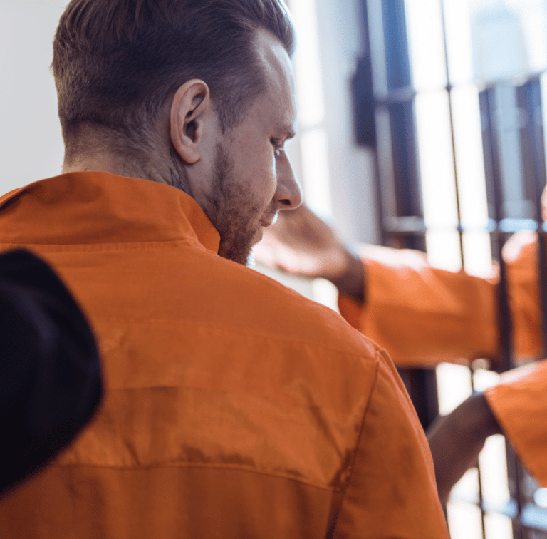 Cropped image of prison guard leading prisoner