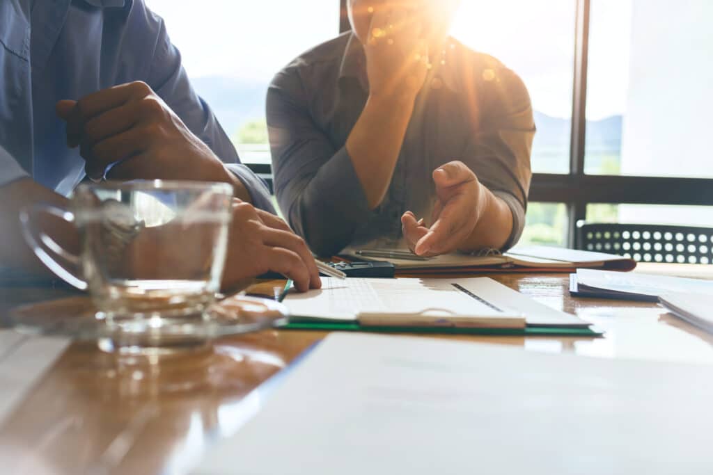 Two men at a conference room table looking at a document on a clipboard
