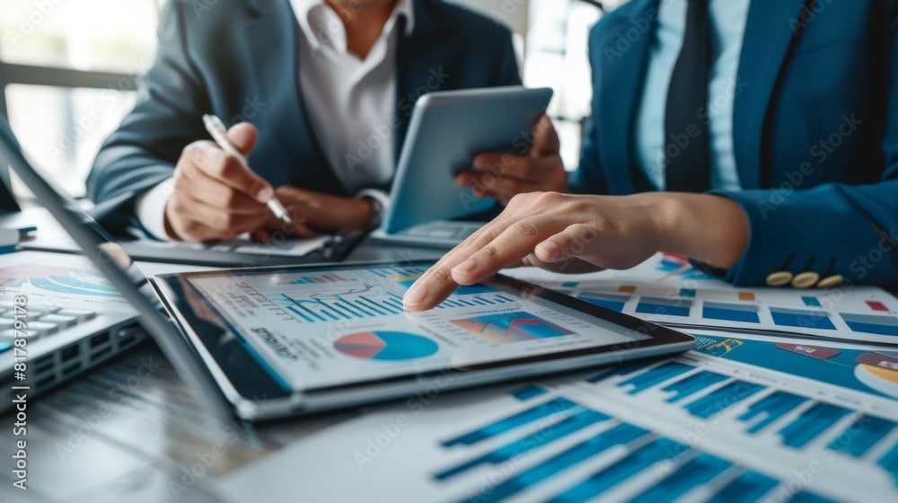 Business people looking at charts on a tablet at a conference room table